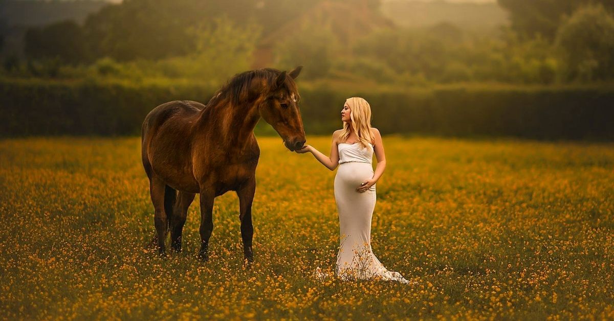 a pregnant woman feeding a brown horse